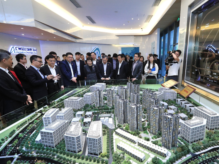 Group of people viewing a model of a city development, inside a building.